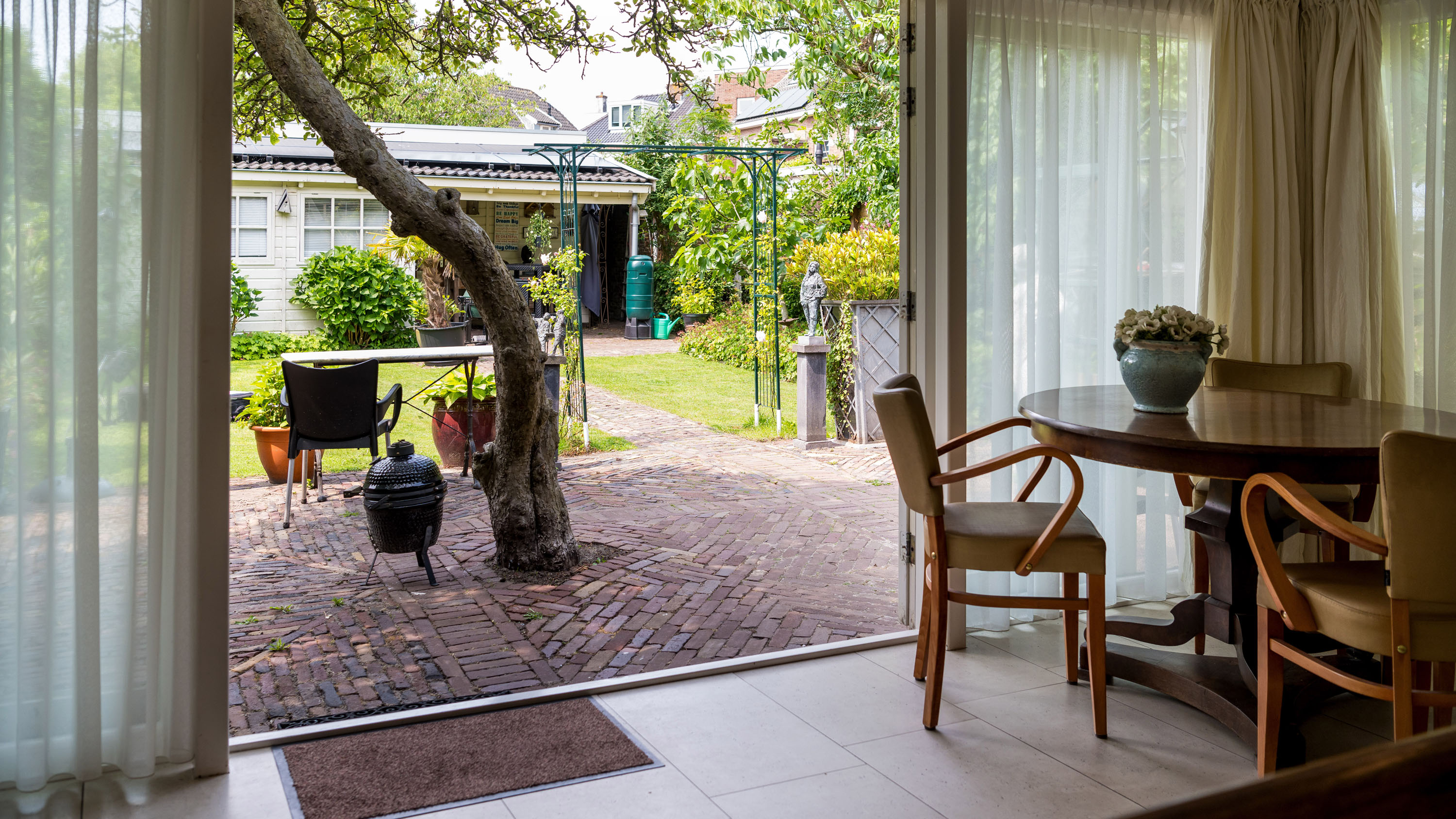 Huisje nassau met groene bomen en een kas ernaast